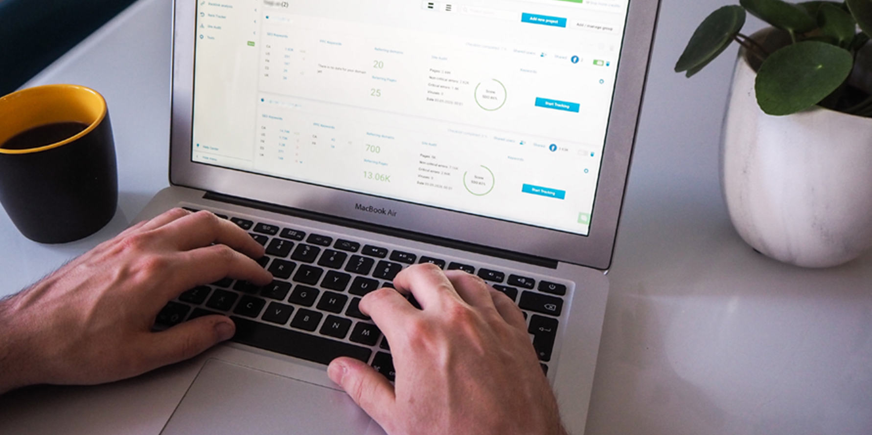 Photograph of a revenue leader's hands typing on a MacBook Air displaying a sales analytics report