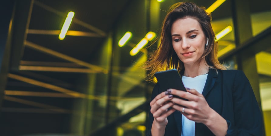 Photograph of revenue leader tapping on a smartphone with AirPod in ear