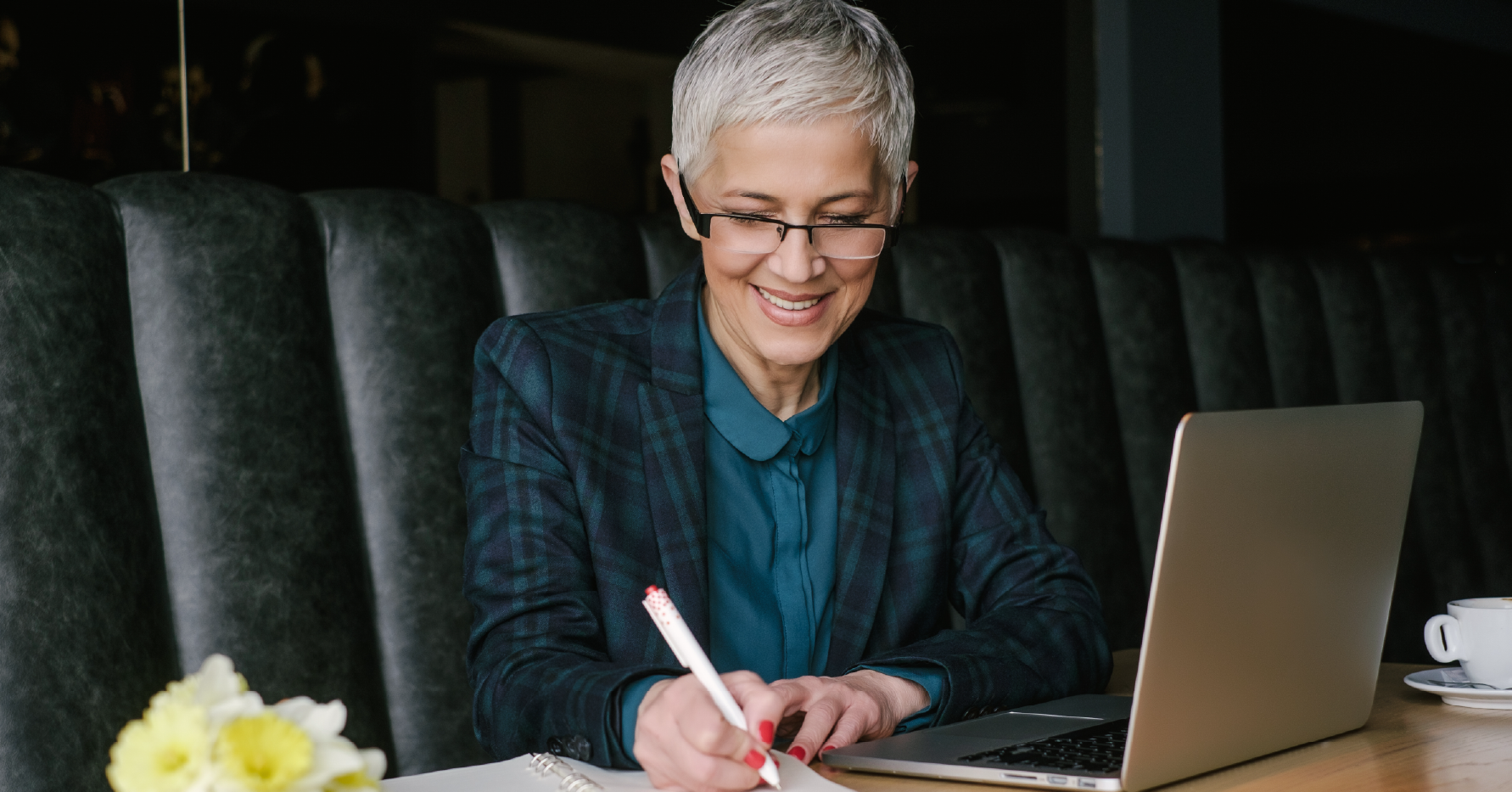 Photograph of a CRO writing in a notebook next to a laptop