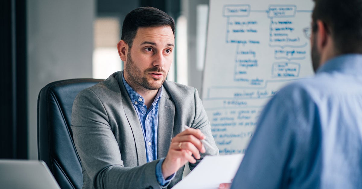 Man in grey suit meeting with another man in an office