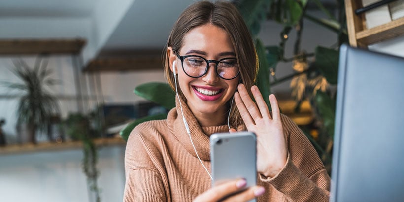 Photograph of a salesperson holding an iPhone and waving on a video call