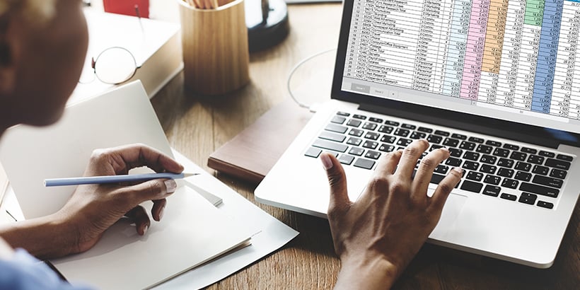 Photograph of a revenue leader looking at a sales forecast spreadsheet on a laptop