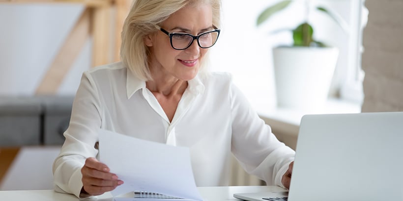 Photograph of a chief financial officer looking at reports in front of a laptop