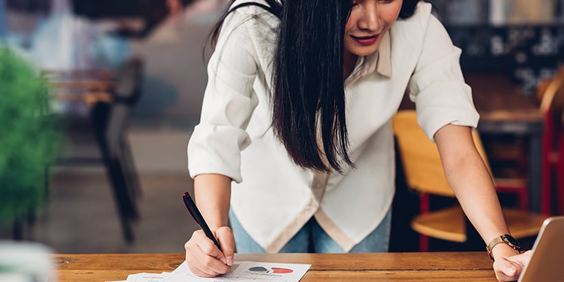 Photograph of a sales leader standing at a table and reviewing sales reports