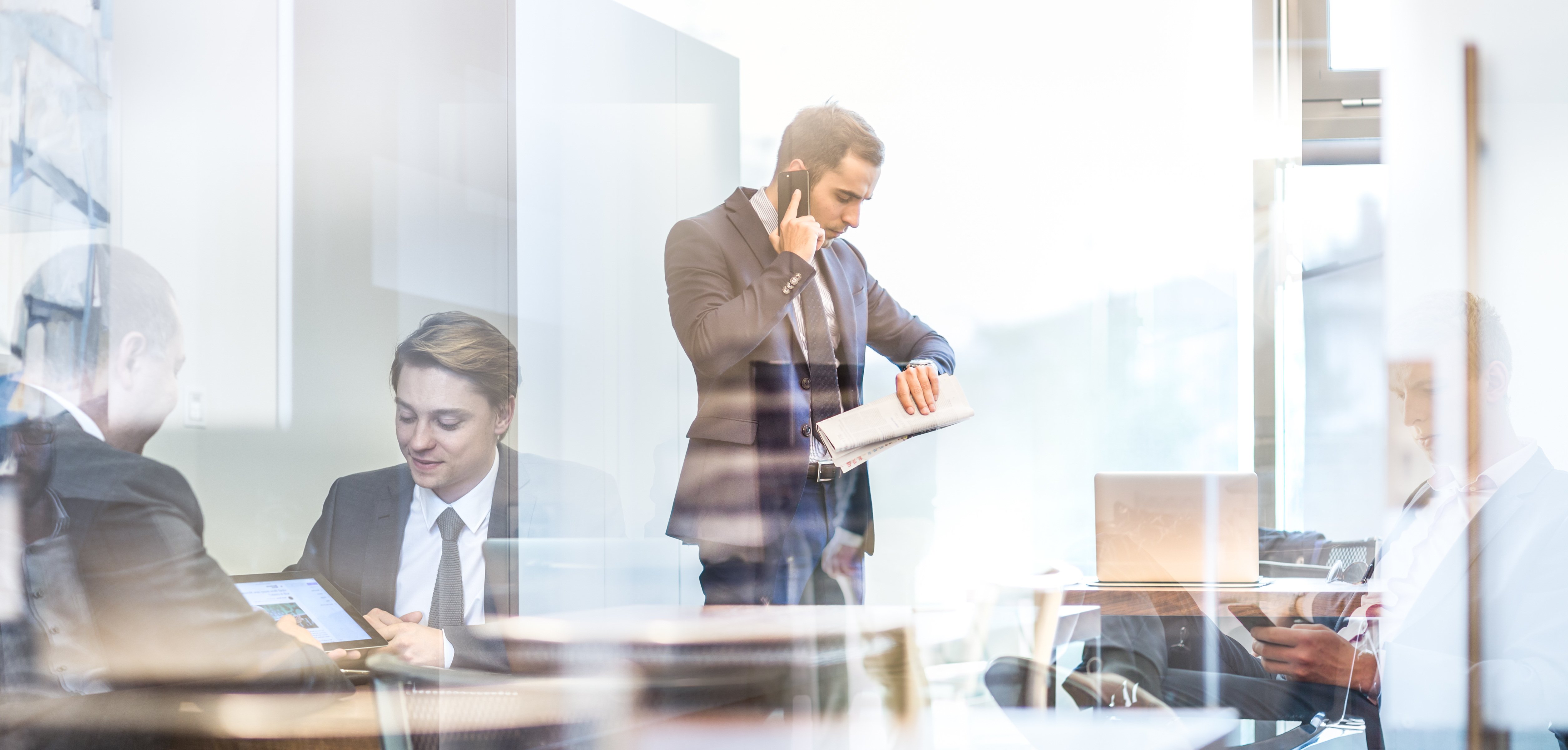 Photograph of a busy CFO talking on cell phone and looking at watch in an office