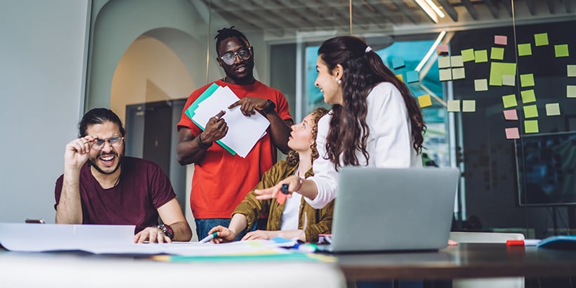 A diverse group of coworkers smiling and laughing at a conference table