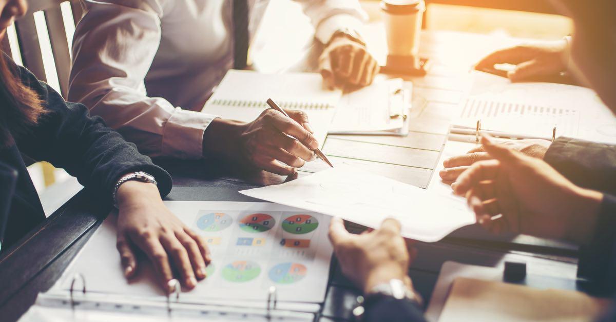 Photograph of sales leaders discussing forecast reports at a conference table