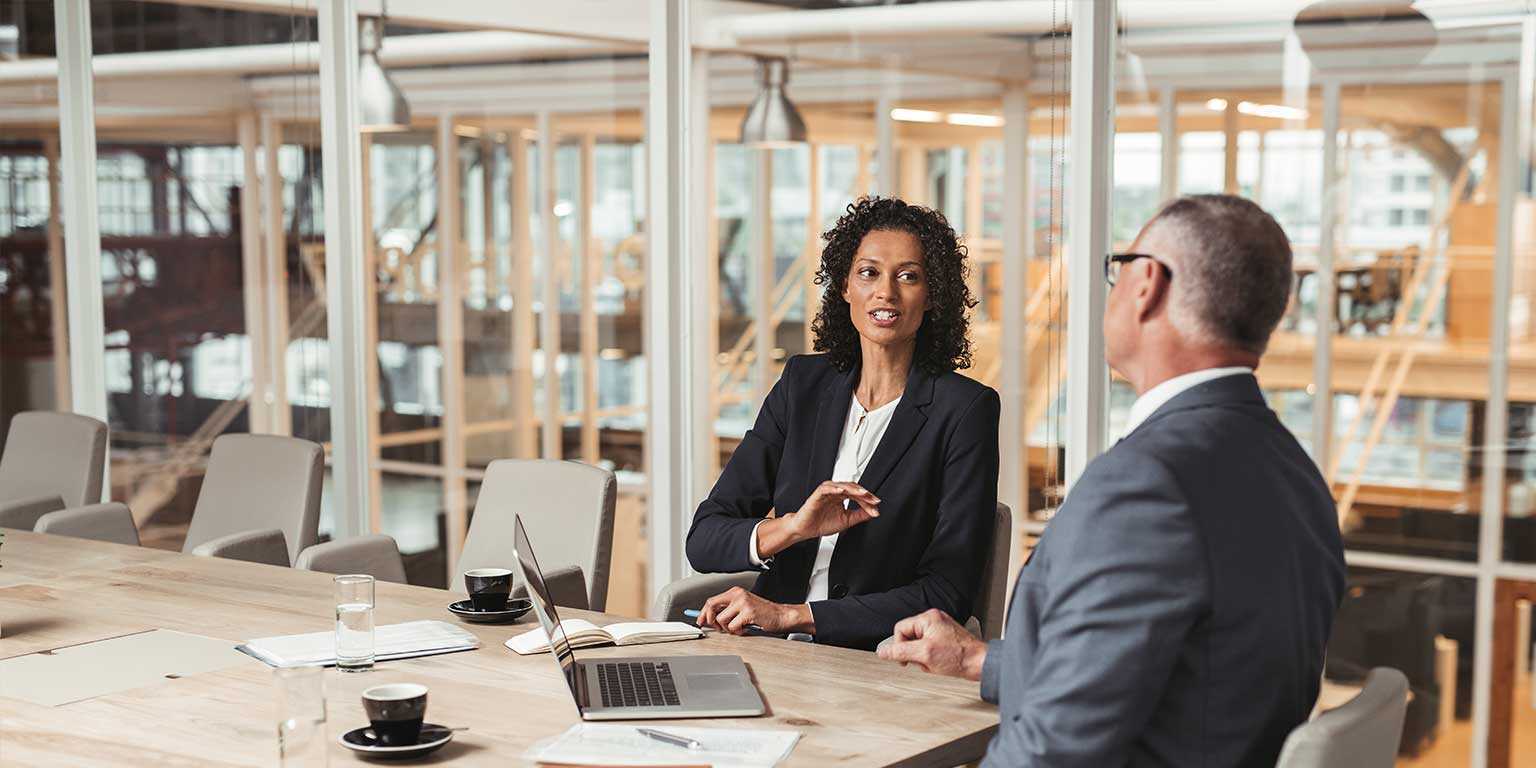 Photograph of two sales leaders sitting  in front of a laptop at a conference table discussing the sales forecast