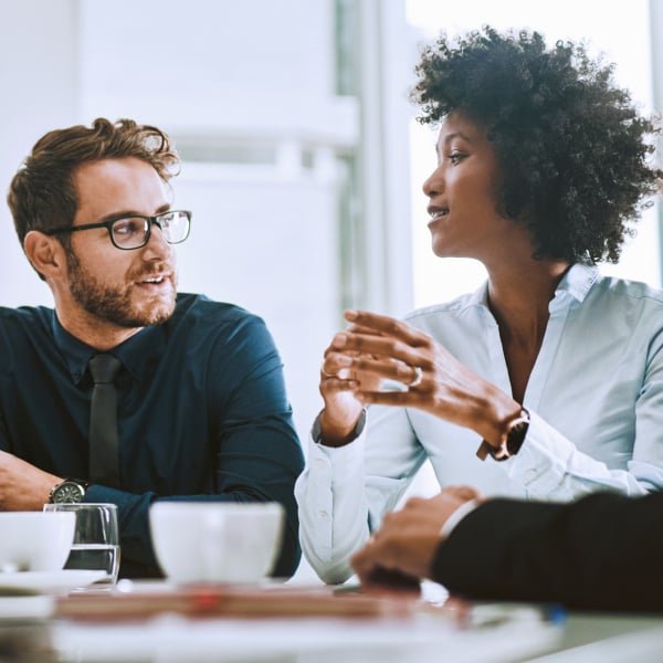 Photograph of three revenue operations professionals talking at a conference table